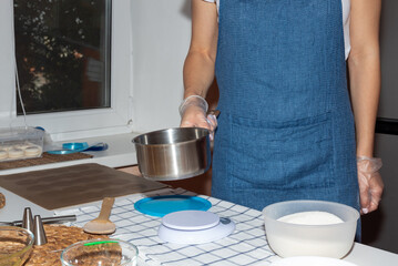 A girl holds a metal bucket in her hands while cooking.