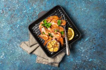 Spicy fried shrimps on grill pan with lemon, garlic and green parsley