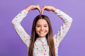 Photo portrait of girl making heart with hands out of self isolated on bright purple colored background