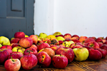 Red and yellow apples in the corner on the floor. Defocused, close up