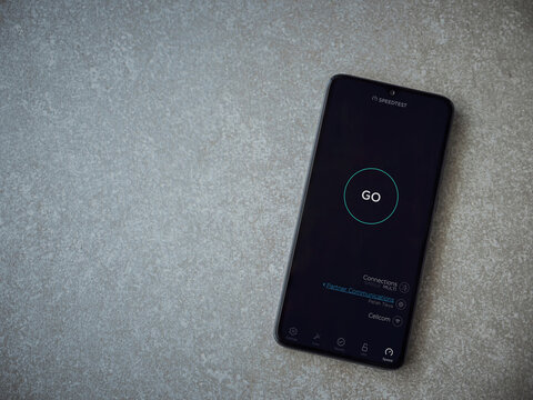 Lod, Israel - July 8, 2020: Speedtest app launch screen with logo on the display of a black mobile smartphone on ceramic stone background. Top view flat lay with copy space.