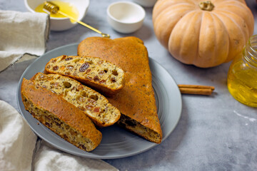 Homemade sugar-free pie with pumpkin, almond flour, poppy seeds, raisins and honey, cut into pieces on a plate surrounded by ingredients, close-up. Healthy pumpkin cake. Keto diet, gluten free baked
