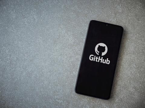 Lod, Israel - July 8, 2020: GitHub app launch screen with logo on the display of a black mobile smartphone on ceramic stone background. Top view flat lay with copy space.