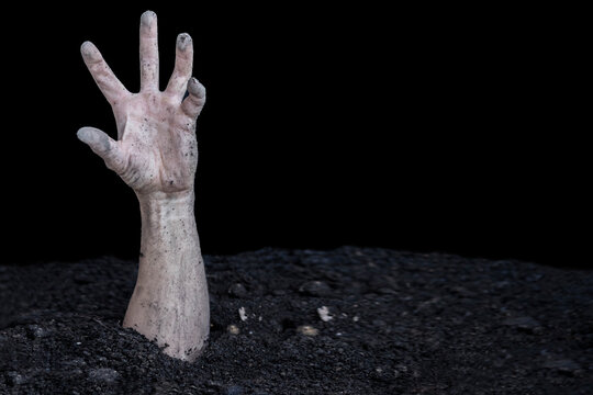 A dirty human hand bursts out of the ground. Buried alive. Zombie hand.