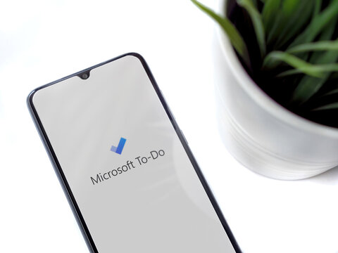 Lod, Israel - July 8, 2020: Modern minimalist office workspace with black mobile smartphone with Microsoft To Do app launch screen with logo on white background. Top view flat lay with copy space.