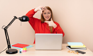 Young student woman in a workplace with a laptop focusing face. Framing symbol