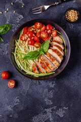 Fried chicken fillet and fresh vegetable salad of tomatoes, zucchini and pine nuts.