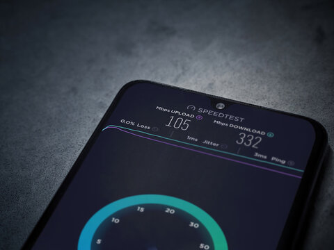 Lod, Israel - July 8, 2020: Speedtest app launch screen with logo on the display of a black mobile smartphone on dark marble stone background. Top view flat lay with copy space.