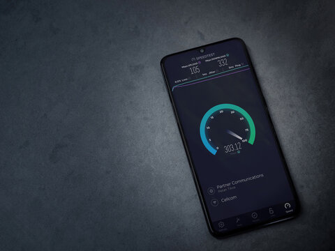 Lod, Israel - July 8, 2020: Speedtest app launch screen with logo on the display of a black mobile smartphone on dark marble stone background. Top view flat lay with copy space.