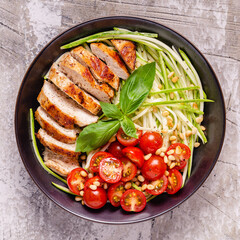 Fried chicken fillet and fresh vegetable salad of tomatoes, zucchini and pine nuts.