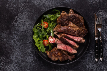 Grilled beef steak with spices on a black plate