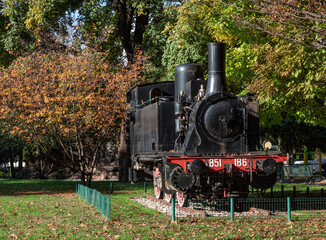 old black steam locomotive displayed in a public park on a sunny autumn day.Como,Italy