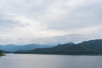 Landscape nature scenery panoramic in the lake dam with mountain over mountains fertile with green forest trees as the background, winter season as the clouds flow above the hills