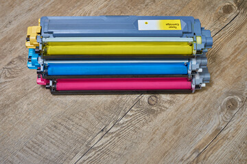 Three toner cartridges for color laser printer stacked on wooden table