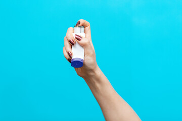 Symptoms of asthma. A woman's hand holds an inhaler with medicine, pressing the pump. Blue background. Copy space