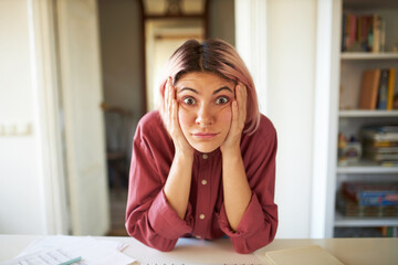 Funny surprised bug eyed young woman with nose ring and pinkish hair looking at camera in full...