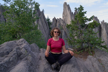 Naklejka na ściany i meble Smiling woman sitting on the top of rock