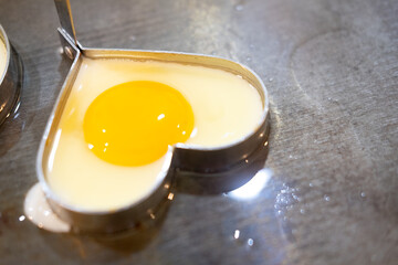 Chef make breakfast with fried egg heart shape at hotel in morning