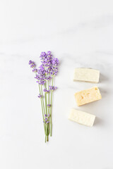 stack of handmade soap, mini lavender bouquet on marble background. flat lay, top view