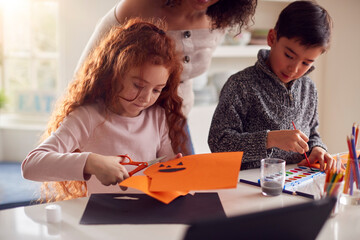 Group Of Children At Home With Mother Having Fun Making Craft Together