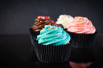 Tasty colorful cupcakes isolated on dark background. Delicious cupcake