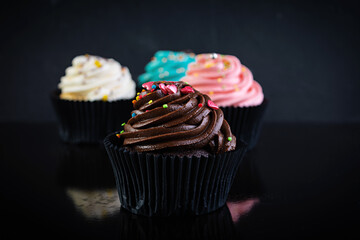 Tasty colorful cupcakes isolated on dark background. Delicious cupcake