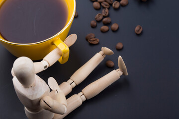 Roasted coffee beans and wooden doll on dark background.