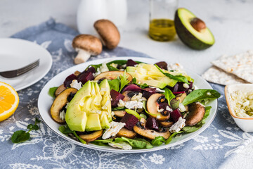 Vegan salad with avocado, beets, mushrooms and salad mix on a white plate