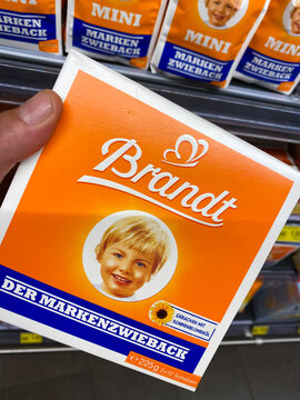Viersen, Germany - July 9. 2020: Closeup of hand holding bag with Brandt rusk crisp breads in german supermarket (focus on center of bag)