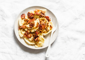 Potato pierogi with fried bacon and onions - delicious homemade lunch on a light background, top...