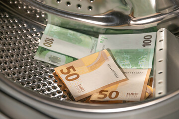 Money laundering concept, pile of euro banknotes are about to be cleaned inside the washing...