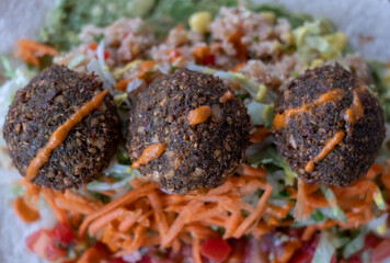 Wrap with falafal balls, colourful salad, with sauce over.
