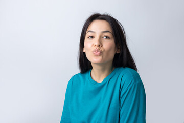 Portrait of flirting young woman blowing air kiss isolated over grey background