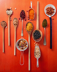 Top view flat lay of assortment of legumes on orange color tabletop