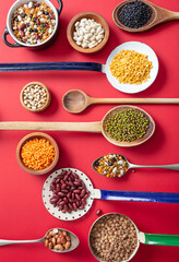 Top view flat lay of assortment of legumes on red tabletop