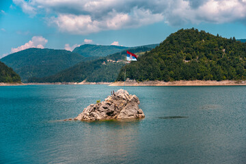 Serbian flag waving on a pole at a lonley island in the middle of Zaovine lake, Tara mountain