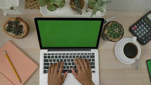 Top view business woman  laptop with green screen, scrolling pages, tapping on touch screen on office desk background. Green screen. Chroma key