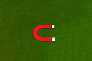 Red magnet on a green background. The concept of gravity, of an electric discharge.