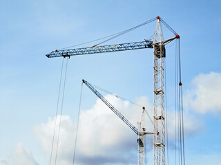 Two construction cranes against the sky