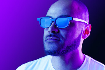 Fototapeta premium Positive black man in glasses posing in neon lights
