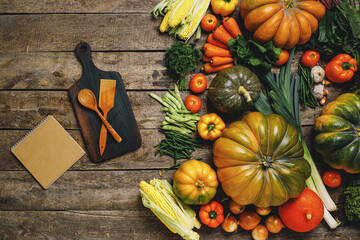 Wooden cutting board with autumn vegetables on wooden table