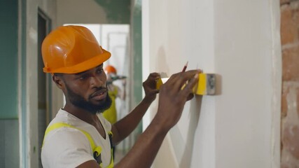 African male worker checking level of the wall with the bubble level tool