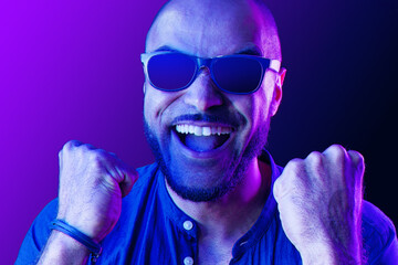 Obraz premium Black man in glasses shouting with happiness in neon light