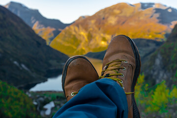 Hikers feet and boots with the view of a Norwegian fjord in the background. Blurred background.