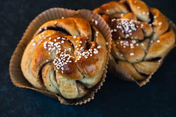 Rustic cinnamon buns with sugar on top placed on dark stone surface