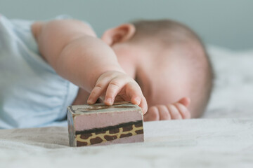 6 month old baby grasping vintage wooden block