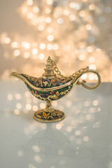  A gold genie  Aladdin lamp on  blurred shiny with glitter sparkle light white  background