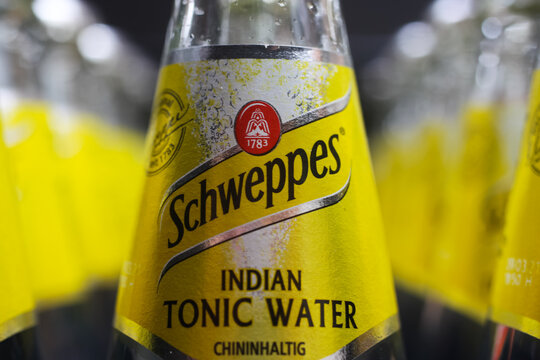 Viersen, Germany - May 9. 2020: Close up of yellow Schweppes Indian tonic water bottle in container (selective focus on center)