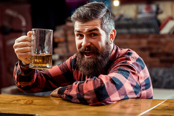 Bearded man drinking beer. Handsome guy sitting at the bar counter. Beer pub.