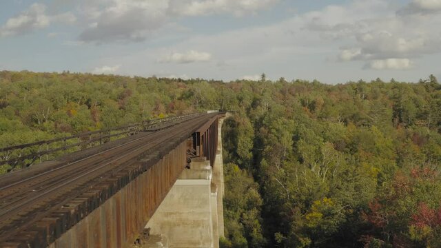 Flying beside a rusty railroad trestle during an early fall golden hour AERIAL
